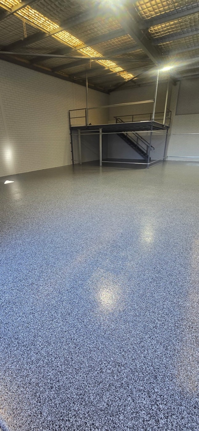 Blue-grey flake epoxy floor in a Perth warehouse unit with mezzanine